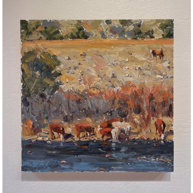 This oil painting captures a serene riverside scene where cattle graze along the water's edge, their reflections...