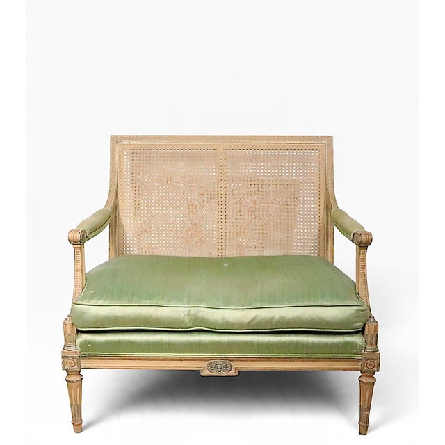 Elegant French style cane back settee, with a painted carved wood frame, upholstered arm rests, and a loose cushion seat...