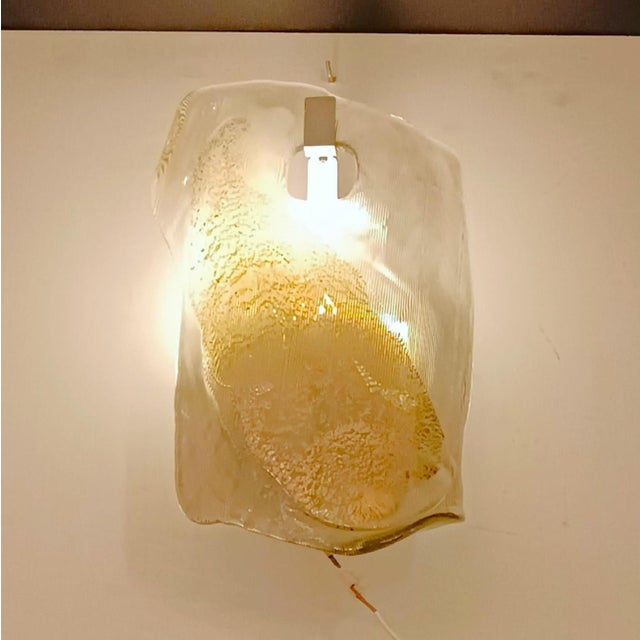 Pair of blown Murano glass wall sconces with smoky tones in which subtle details in golden tones glide smoothly. European...