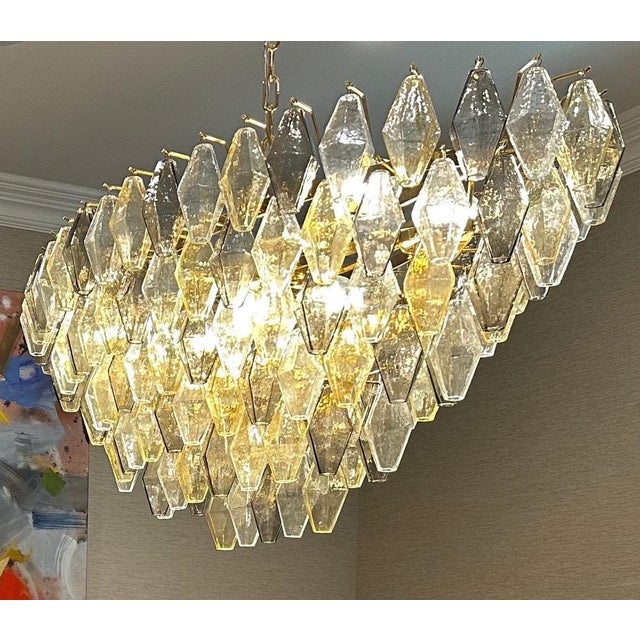 This chandelier consists dozens of hand blown gray, amber and clear "Poliedri" made of Murano glass with a brass frame....