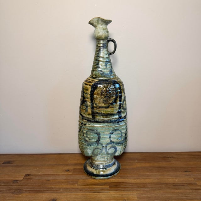 A striking tall studio pottery ewer with a strong sculptural presence and a very expressive hand-built look. The form is...
