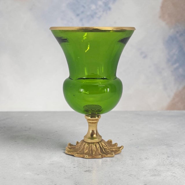 A decorative footed art-glass vase of compact scale, combining saturated lime-green transparent glass with gold-finished...