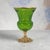 A decorative footed art-glass vase of compact scale, combining saturated lime-green transparent glass with gold-finished...
