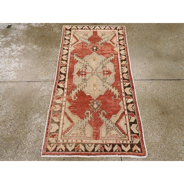 A vintage Turkish Oushak throw rug. Vigorous sawtooth leaves project from the medallion and corners into the red field of...
