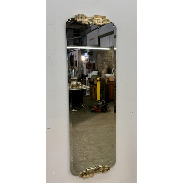 Italian wall mirror featuring a smoked glass panel with rounded corners and sculptural gilt-metal appliqués at the top and...