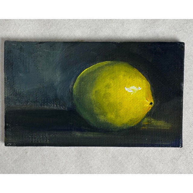 This small vintage original oil painting on canvas board depicts a single lemon resting on a dark surface, rendered in a...