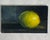 This small vintage original oil painting on canvas board depicts a single lemon resting on a dark surface, rendered in a...