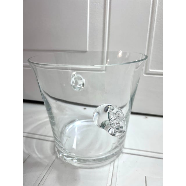 This is a clear glass ice bucket with swirled scroll handles, similar to vintage designs by Tiffany & Co.. Bucket is in...