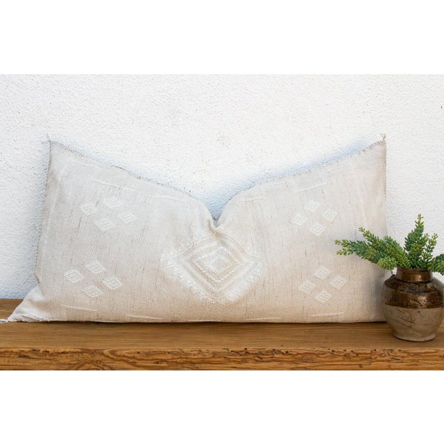 A central diamond medallion, stitched in tone-on-tone white, anchors this handcrafted Moroccan cactus silk lumbar pillow —...