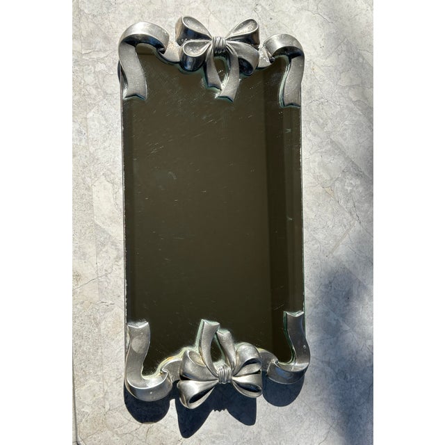 Hollywood Regency Mirrored Tray with Bow Details An elegant mirrored tray featuring cast metal ribbon-and-bow detailing at...