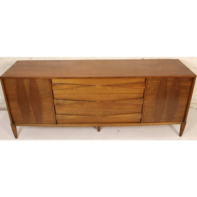 This is mid-century walnut credenza. The piece features sculpted drawers along with an inlayed diamond pattern on door...
