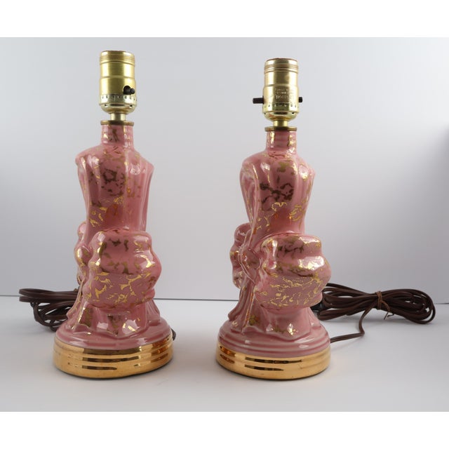 A striking pair of vintage ceramic table lamps in a sculptural bow form, finished in glossy rose pink with scattered gold...