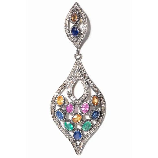 A mosaic of oval, faceted, colored (blue, pink, yellow and green) sapphires in a bezel setting bordered in pave`-set...