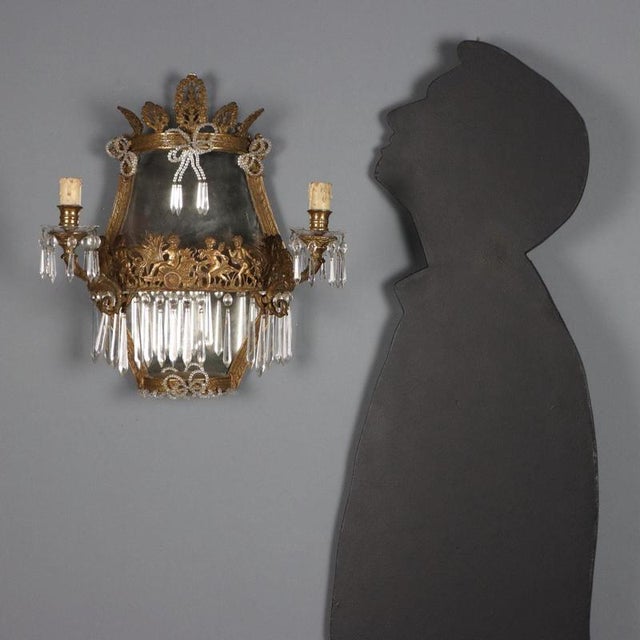 Pair of gilded bronze wall lamps with neoclassical motifs. Two lights supported by curved arms, clear glass bobeches,...