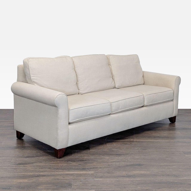 This Pottery Barn 3-seat sofa features a classic beige fabric and stylish rolled arms. It offers comfortable seating with...