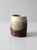 This studio pottery vase features an organic form and a rich earth-tone glaze blending creamy whites, soft beiges, and...