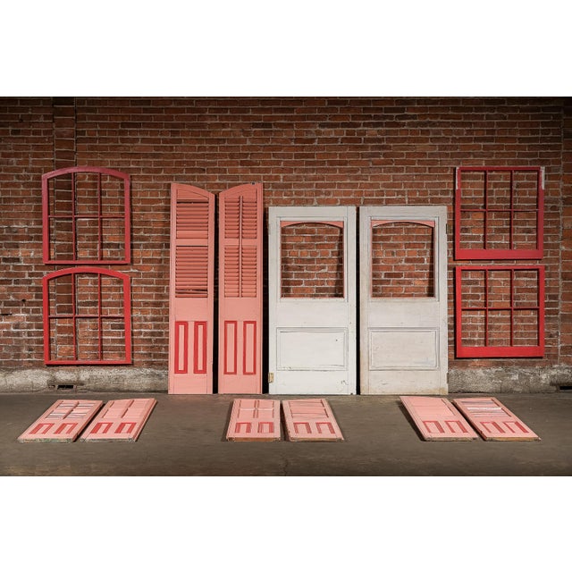 A vibrant, salvaged architectural ensemble sourced directly from New Orleans, comprising doors, shutters, and window...