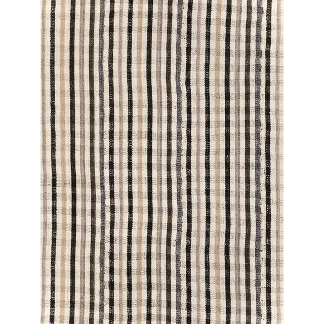 This early 20th-century Persian flatweave kilim room-size carpet presents a striking minimalist composition of narrow...