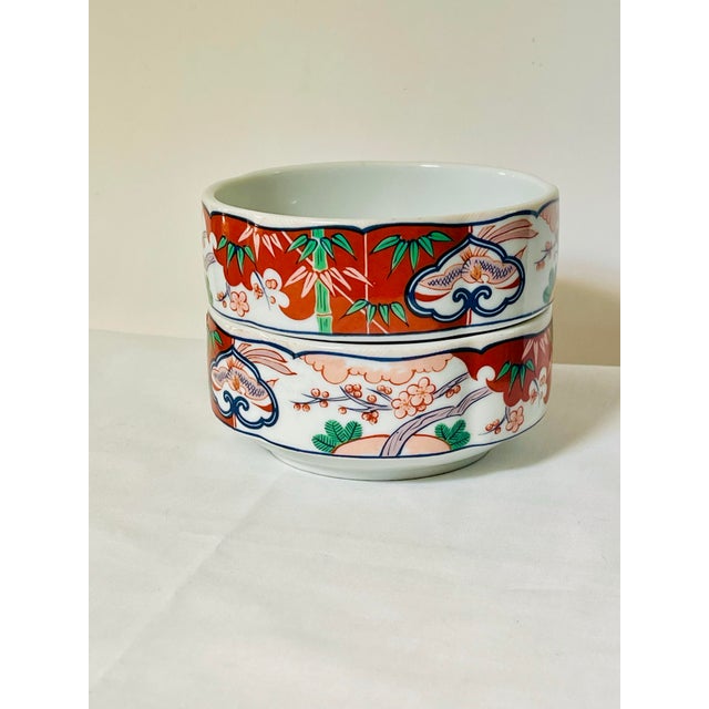 A pair of vintage Asian inspired bowls decorated with bamboo, cherry blossoms and birds on a red and white background....