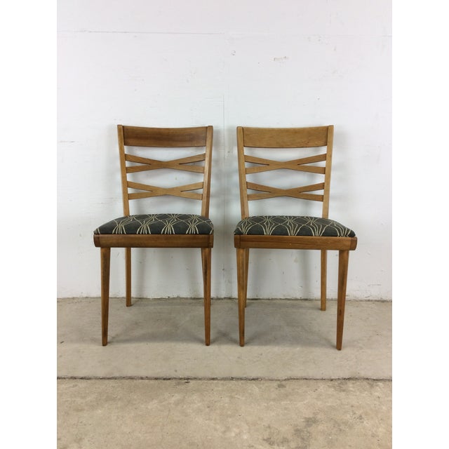 This pair of dining chairs by Heywood Wakefield feature hardwood construction, original champagne finish, newer patterned...