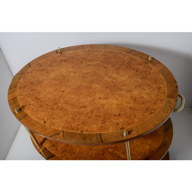 This is a striking Burl Veneer and Brass three tier table with brass handles that stands on brass casters. It is oval in...