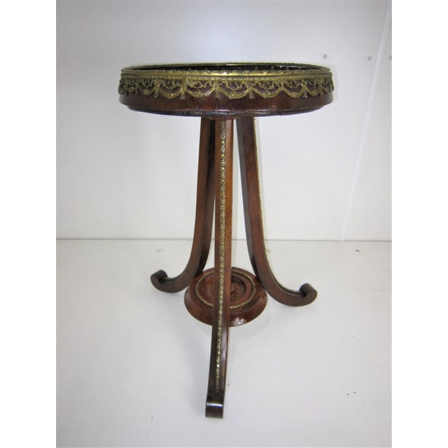 Antique walnut and fruitwood pedestal table with circular top featuring a gallery surround of foliate swag and floral...