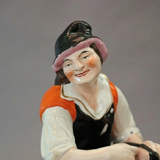 An antique English Staffordshire porcelain figure depicts hand painted cobbler working on shoe seated on covered stool...
