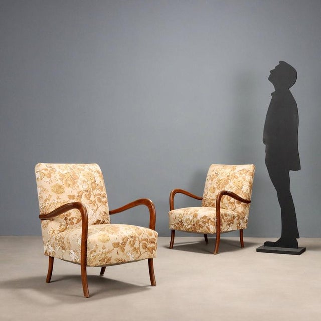 Pair of vintage armchairs with exposed beech wood armrests, sprung and foam padding, and fabric upholstery. These seats...