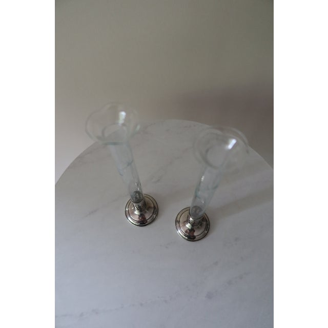 An elegant and refined pair of antique bud vases, each combining a slender etched glass tube with a weighted sterling...
