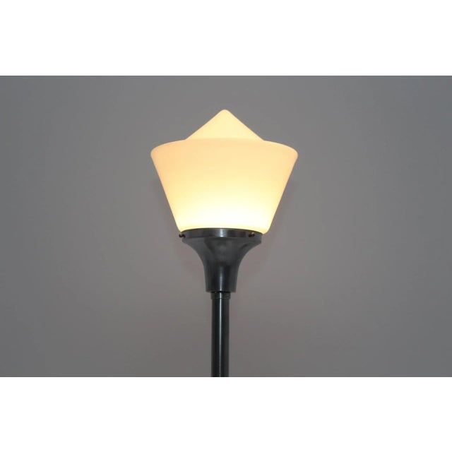 This Art Deco table lamp comes with a cast iron base, featuring an aluminum frame and a glass shade made of opaline glass....