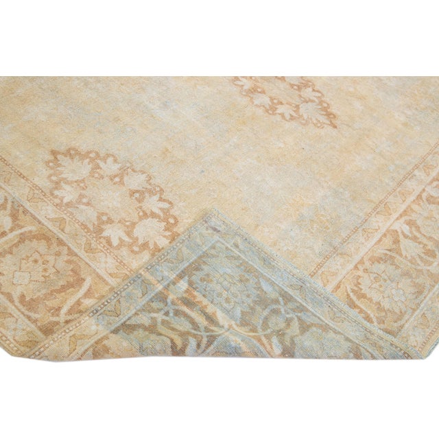 Beautiful antique Agra hand-knotted wool rug with a beige color field. This Indian rug has brown and blue accents in a...