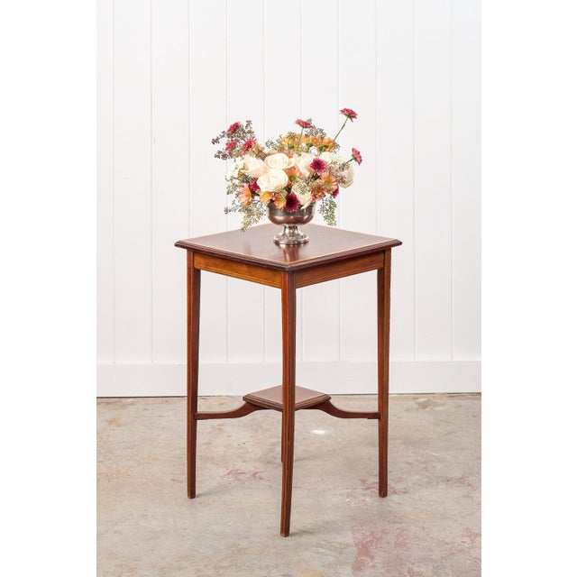 This square Edwardian two-tier side table features a finely inlaid banding along the top, bottom shelves and detailing...