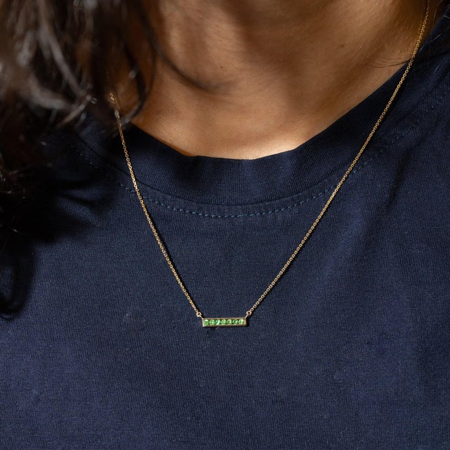 Seven green Zambian emeralds station a solid 14K yellow gold chain, 16-18" adjustable, totalling 0.24cttw. Zambian...