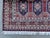 A finely hand-knotted Afghan rug in the classic Caucasian Shirvan style — nine vase-and-blossom panels sit within a bold...