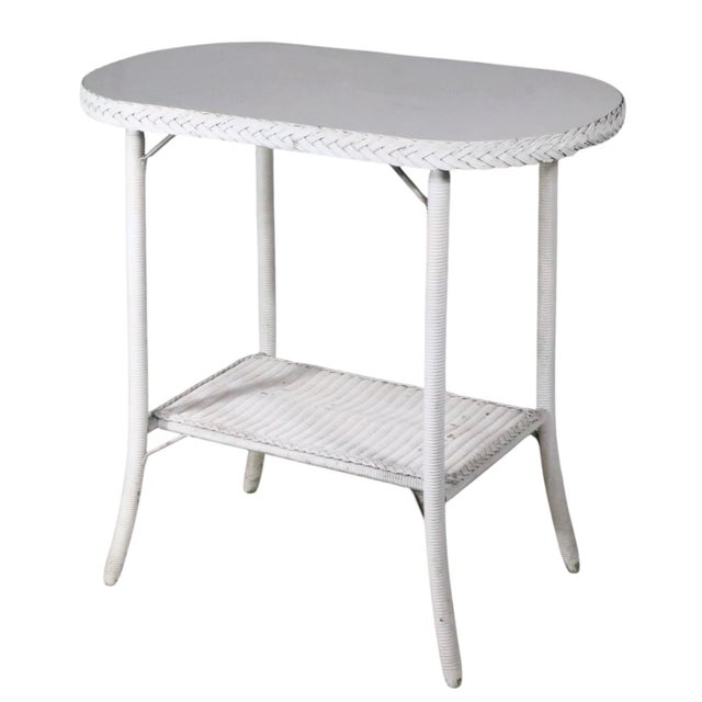 Classic white wicker oval side table attributed to the Lloyd Loom Furniture Company. The table features an oval top with...