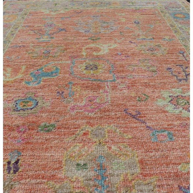 This very unique piece has a wide array of bright colors, starting with a faded orange background and a light lilac...