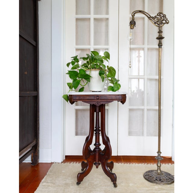 This ornate Eastlake Victorian parlor table, plant stand, or side table boasts an ornate apron and its original soapstone...