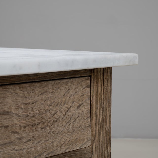 This 19th Century French Louis XVI oak chest of drawers with a marble top presents a refined balance of neoclassical...