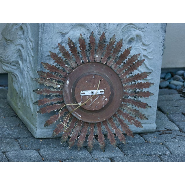 A Spanish gilt metal sunburst light fixture from the Midcentury period, with pierced stars and foliage. This exquisite...