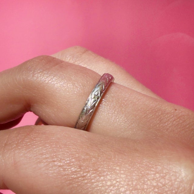 About This Ring: A timeless platinum band carrying the gentle marks of a life well-lived. Delicate engraving reveals a...