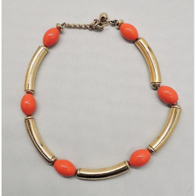 This is part of Chairish’s Costume Jewelry assortment. 1970s goldtone tubular sections with orange glass beads necklace...