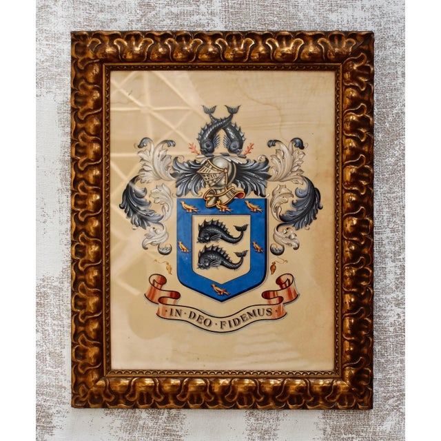Antique edwardian heraldic crest, hand painted with a central shield depicting 2 dolphins and birds, below is a banner...