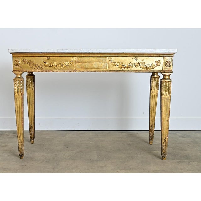 A robust 18th century Italian console table with an exquisite giltwood base supporting its original, thick slab of white...