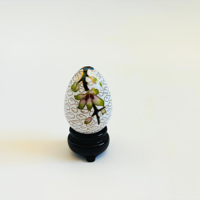 A small vintage cloisonne egg incense holder on a black wood stand. Lovely floral pattern separated by lines of brass. A...