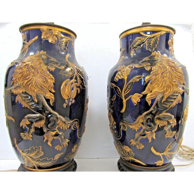 This is a pair of antique French porcelain polychrome faience vases with a lion rampant design, served as table lamps....