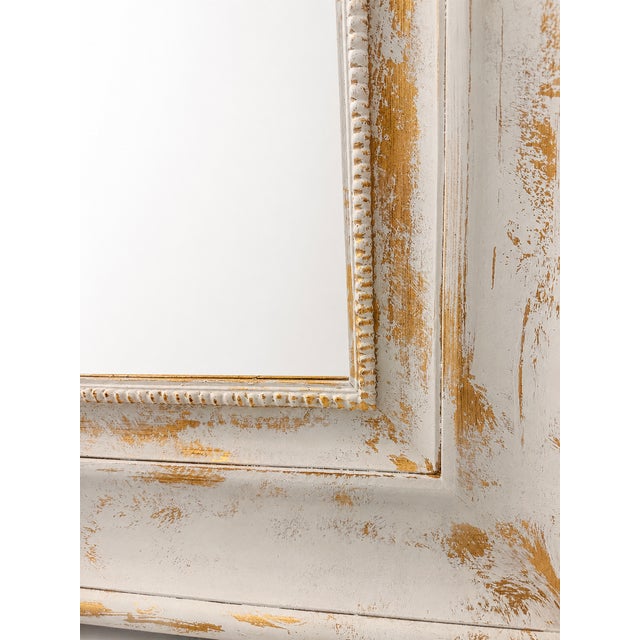 A beautifully handcrafted oversized wall mirror featuring an elegant distressed white finish enhanced with warm antique...