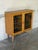This cabinet features an enclosed silhouette supported by four tapered legs. Two prominent doors showcase multi-colored...