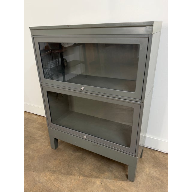 A substantial vintage industrial barrister bookcase or display cabinet constructed entirely of steel and finished in a...