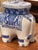 A blue and white ceramic elephant stool with a flat oval seat and four molded legs. The body is decorated with painted...