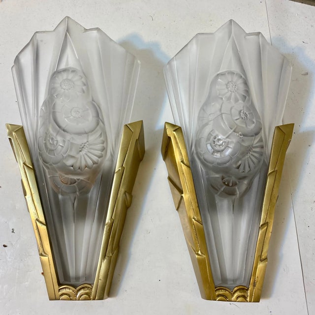 Pair of French Art Deco wall sconces by the French artist Degue. Clear frosted glass shades decorated with geometric and...